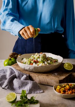 Midsection of woman squeezing lemon juice on cod ceviche