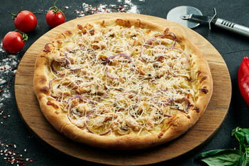 Pizza with a large number of toppings: chicken, onions, mushrooms, cheese and creamy sauce. Pizza in composition with ingredients on a black background