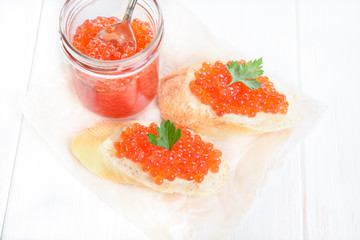Top view of snacks with red caviar on white