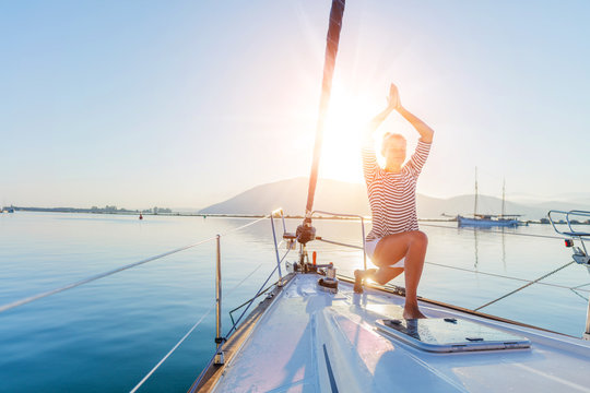 Girl is practicing yoga on the deck of the yacht boat