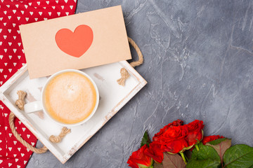 Close-up. Valentine's Day concept. Morning coffee, envelope with heart, roses on grey desk. Free space. Space for text. 