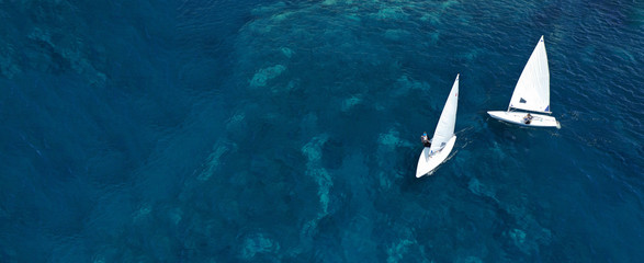 Aerial drone ultra wide photo of children practising with small sail boats in Mediterranean bay with deep blue sea