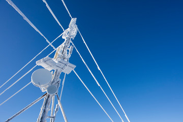 pole with antenna and frozen wire. clear blue sky in winter