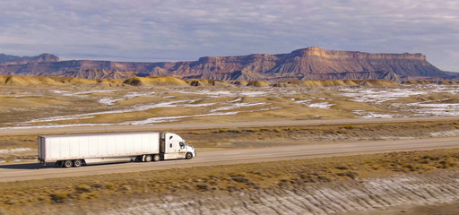 AERIAL: Semi-trailer truck speeds along the motorway running across the desert © helivideo