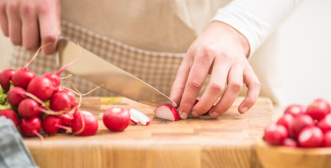Obraz na płótnie Canvas Woman slicing fresh radish at home in kitchen