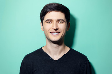Studio portrait of young smiling man on background of aqua menthe color.