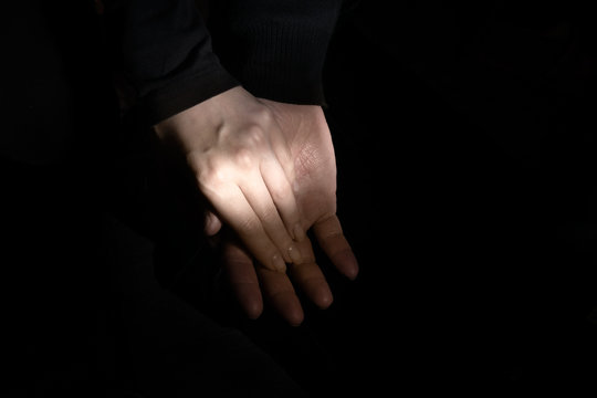 male and female hands in a gentle touch on a black background