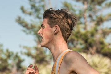 Close-up of Caucasian teen male cross country runner sweating in race