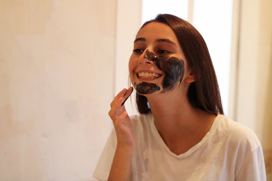 Young and attractive girl applying a brown sugar mask.