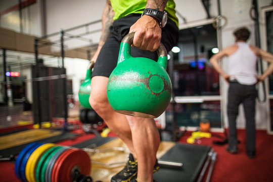 Cropped view of man holding Kettlebells at the gym.