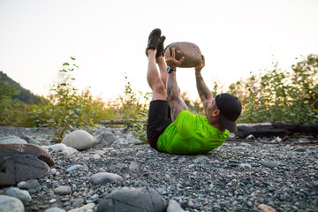 Fit man uses boulder in outdoor fitness routine