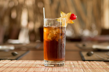 Dark Iced tea with tropical fruit in the glass over a wood table