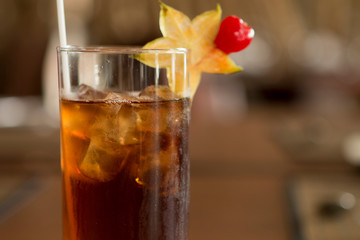 Dark Iced tea with tropical fruit in the glass over a wood table closeup