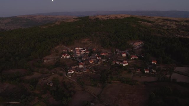 Old rural village top shot located on the mountains. Moon on the frame. Shot at dusk by drone