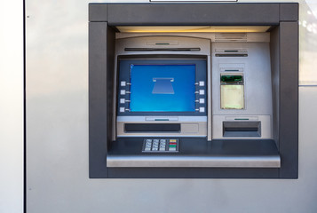 Silver atm machine with screen and buttons is in building wall, nobody - obrazy, fototapety, plakaty