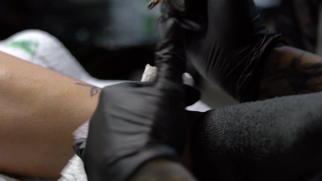 Tattoo female artist makes a tattoo on a female leg.