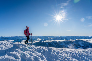 nice senior woman snowshoeing on the Nagelfluh chain above a sea of fog over Bregenz Wald...