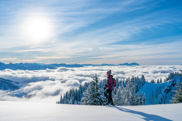 nice senior woman snowshoeing on the Nagelfluh chain above a sea of fog over Bregenz Wald mountains, Hochgrat, Steibis,Bavarian alps, 