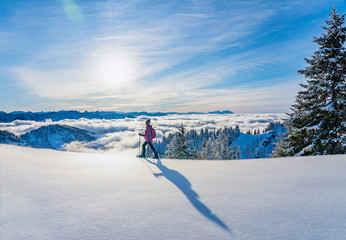 nice senior woman snowshoeing on the Nagelfluh chain above a sea of fog over Bregenz Wald...