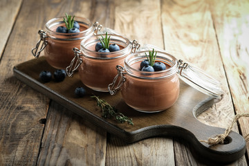 Chocolate mousse in glass jar with berries on a rustic background copy space. Homemade dessert.