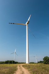 rotating blades of a windmill propeller on blue sky background. Wind power generation. Pure green energy.