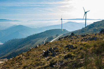 Wind Turbines at Baloiço da Boneca in Portugal Mountain region with mist blue sky in the background