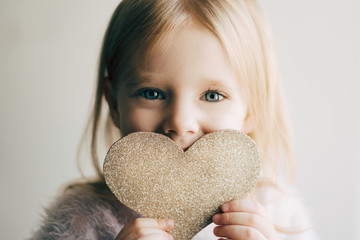 Valentines day. Little girl with a heart. Portrait of a little girl holding valentine's card. - 313675907