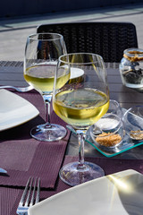 Table served for dinner on outside terrace with glasses of cold white wine and sea view