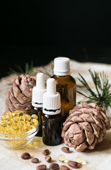 natural product, glass bottles with oil, pine cones with nuts on a tablecloth on a black background, close-up