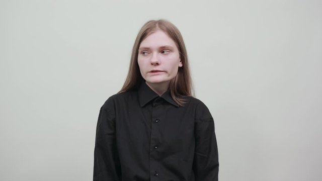 Disappointed young woman in fashion black shirt isolated on gray background in studio looking at camera, unhappy, puffed out her cheeks. People sincere emotions, lifestyle concept.