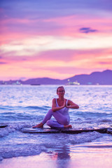 Fototapeta na wymiar Woman practices yoga at seashore