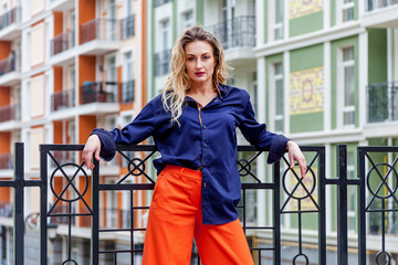 Naklejka premium An outdoor portrait of an attractive woman in bright trousers on the background of buildings