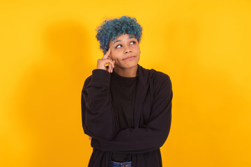 Fototapeta na wymiar young african american girl or woman with blue hair isolated on yellow background