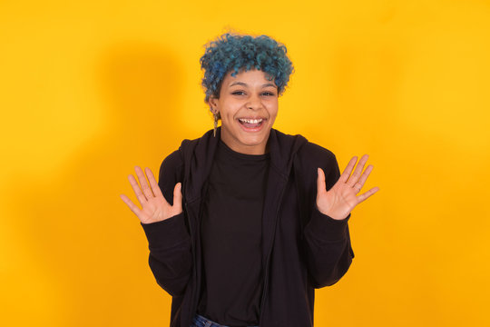 young african american girl or woman with blue hair isolated on yellow background