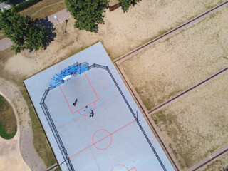 Aerial view of two unrecognizable teen playing basket on a urban court in sunny day