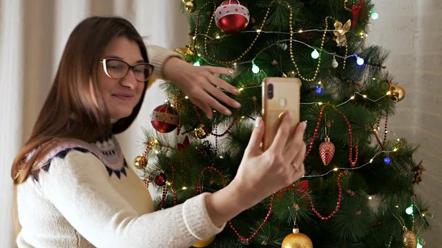 Cheerful young woman taking christmas selfie with smartphone. Holiday, New Year, the concept of happiness
