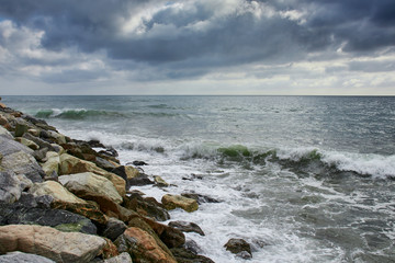Fototapeta na wymiar Cloudy day with waves hitting the coast