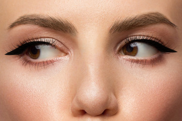 Obraz premium Cosmetics and makeup. Beautiful female eye with sexy black liner make-up. Fashion big arrow forever woman. Great evening makeup, clean makeup and brown eyes. Thick eyebrows and extra long eyelashes