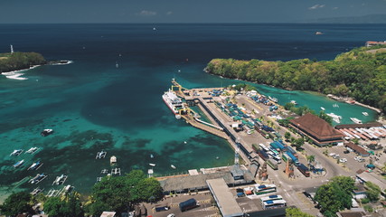 Aerial Flight above Ocean Harbor, Port, Pier and Fishing Boats. Trucks Waiting next Ferry to another Paradise Island. Travel Transport Tourism Concept. Tropical Bali Island, Indonesia