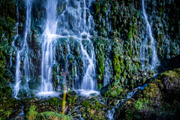 Fototapeta na wymiar Waterfall on stones with vegetation and humidity