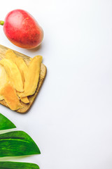 Raw organic dried mango and fresh ripe mango fruit on white background. Healthy eating, raw food or diet concept. Top view. Flat lay
