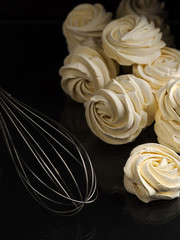 Freshly cooked delicious homemade marshmallows (zephyr) on a dark background. Whisk for whipping dough. Homemade sweets. Vertical orientation.