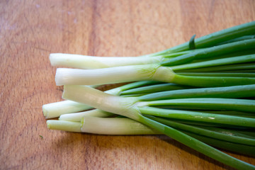 Fresh young onions on wooden table in the kitchen, ready for cooking