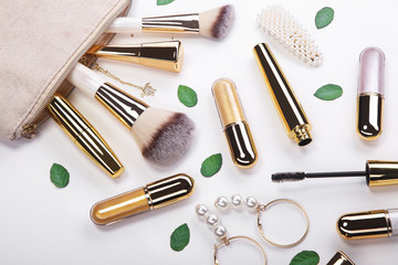 Set of brushes and cosmetic products in a cosmetic bag on a white background.