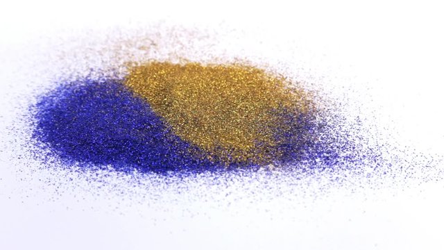 Blue glitter dusts lying on a white background. Gold and silver sparkles or glitter dust fall to a pile on blue glitter dust