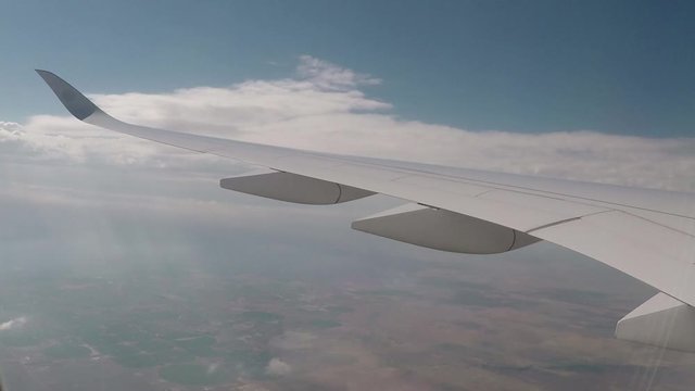commercial passenger jet airplane in mid-flight above clouds timelapse. Airplane window wing view flying above clouds in an airplane.