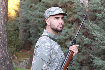  Hunter wearing camouflage clothing in the woods