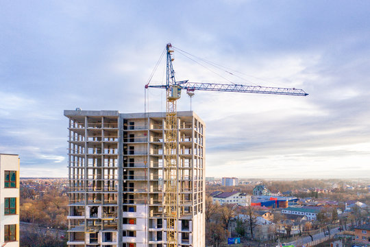 Photo of a multi-storey building under construction. Construction of a residential skyscraper. Background image of the process of building a house with cranes. A high-rise building under construction.