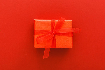 Red present gift with red ribbon on red background. Valentines day love, romance, heart Concept. Valentines day minimal composition top view, flat lay. Stock photo for Anniversary or Date.