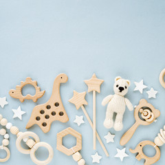 Cute wooden baby toys on light-blue background. Knitted bear,  dinosaur toy, beads and stars. Eco accessories,  beanbag and teethers for newborn. Flat lay, top view